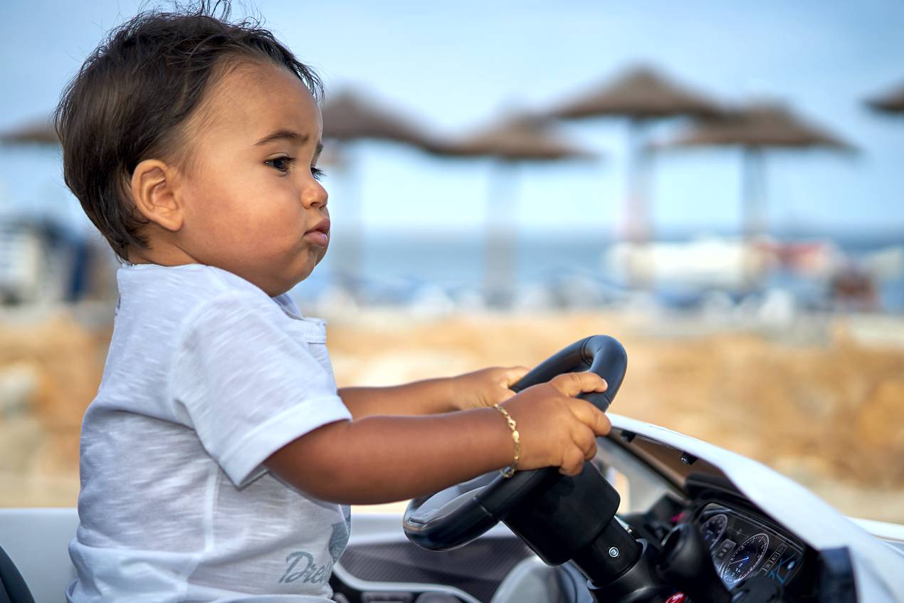 child portrait photo by Ian Tragen - boy driving toy car at the beach